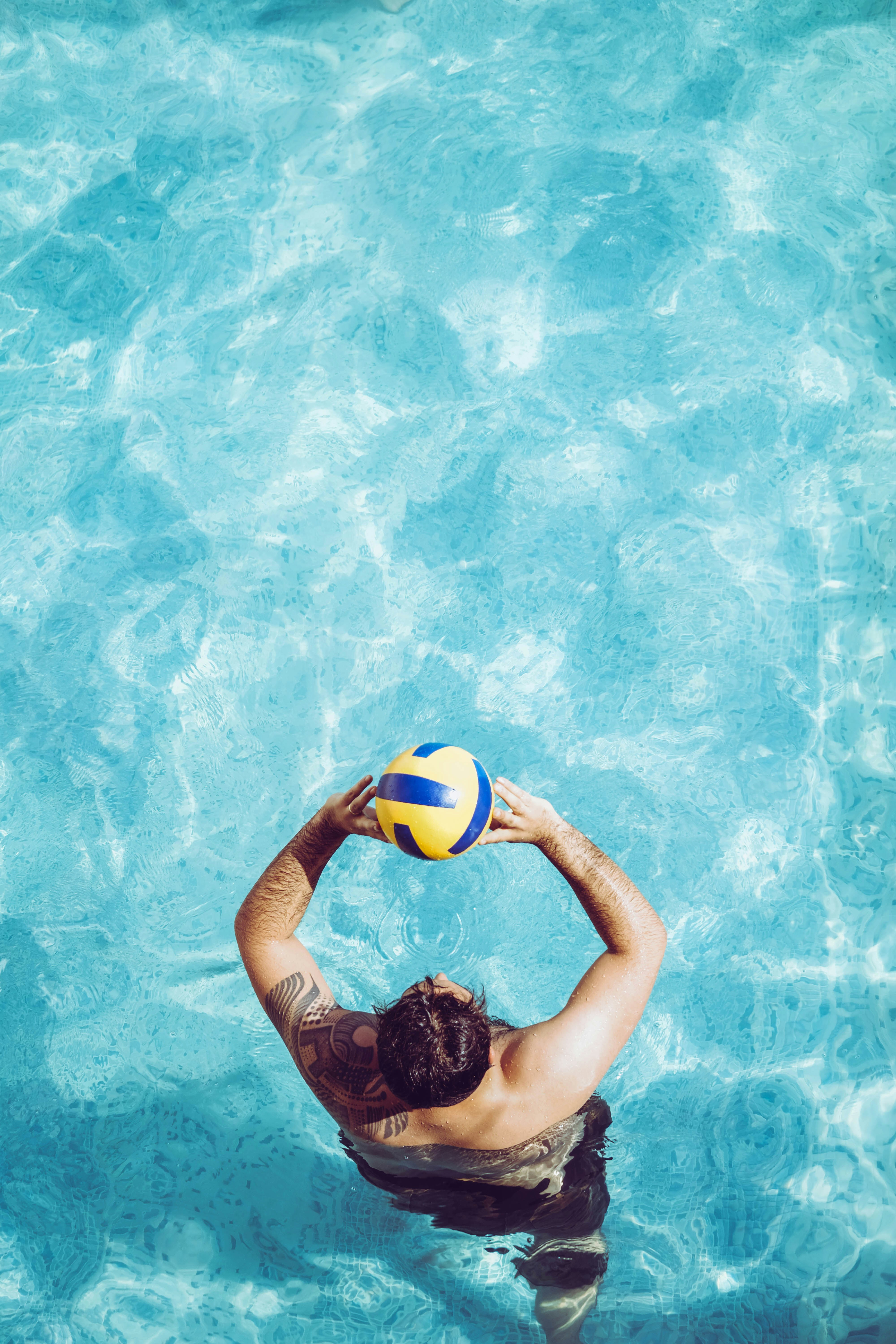 Water polo player holding a ball overhead in the pool